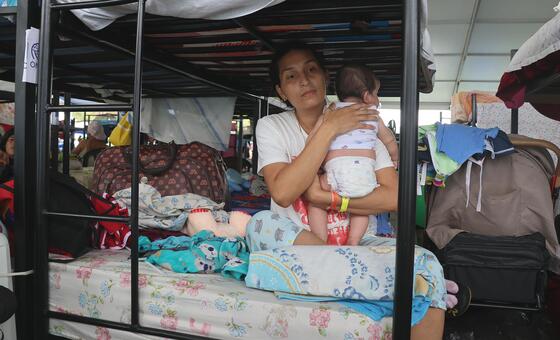 Una mujer desplazada cuida a su hijo de dos meses en un campamento provisional en La Guaira, Venezuela.